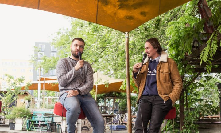 Während der Fuckup Night im Mai 2021 im Urban Spree Berlin unterhält sich der Moderator mit einem Studienabbrecher.