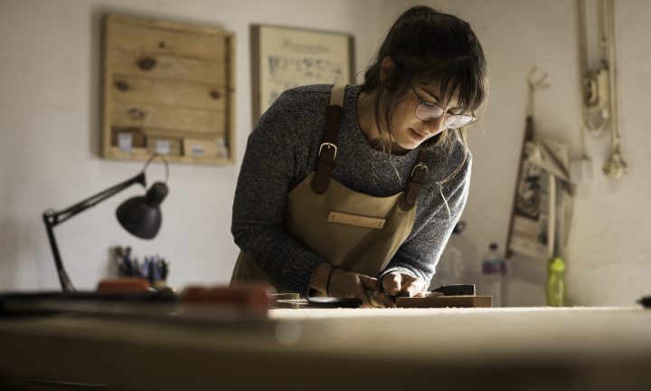 Eine junge Tischlerin arbeitet in einer kleinen Schreinerei.