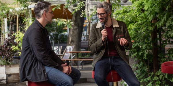 zwei Männer tauschen sich auf einer Bühne aus