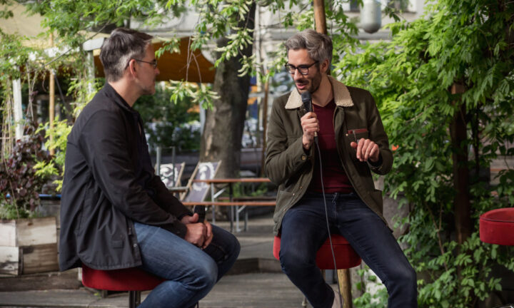 zwei Männer tauschen sich auf einer Bühne aus