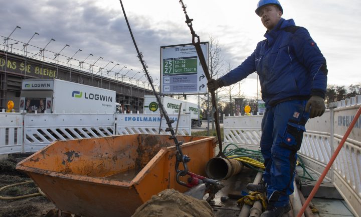 Ein Auszubildender zum Brunnenbauer steht mit blauer Arbeitskleidung auf der Baustelle.