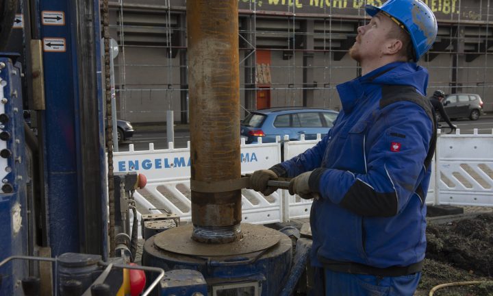Ein Auszubildender zum Brunnenbauer arbeitet mit blauer Arbeitskleidung am Bolzen.