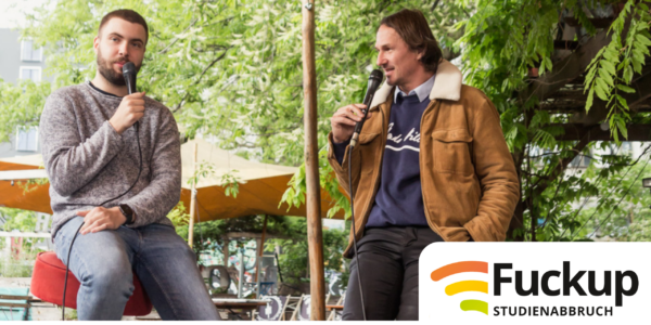 Ein junger Mann sitzt mit dem Moderator auf einer Bühne.