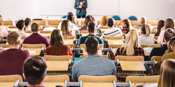 Eine große Gruppe Studierender lauscht aufmerksam einer Vorlesung.