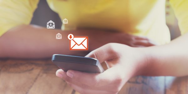 ein Handy wird in einer Hand gehalten, über dem Handy erscheinen Mitteilungssymbole