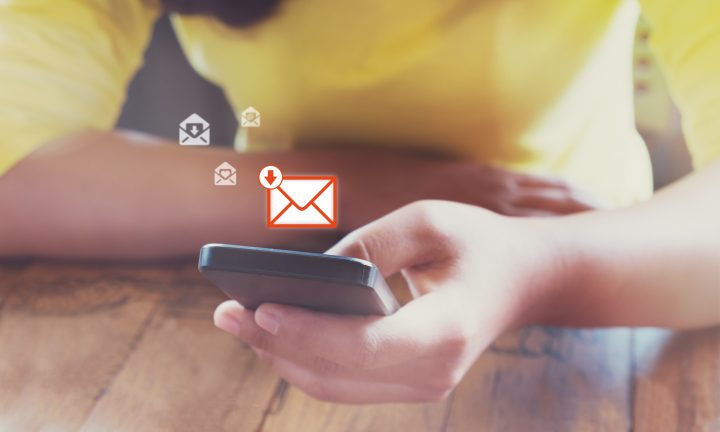 ein Handy wird in einer Hand gehalten, über dem Handy erscheinen Mitteilungssymbole