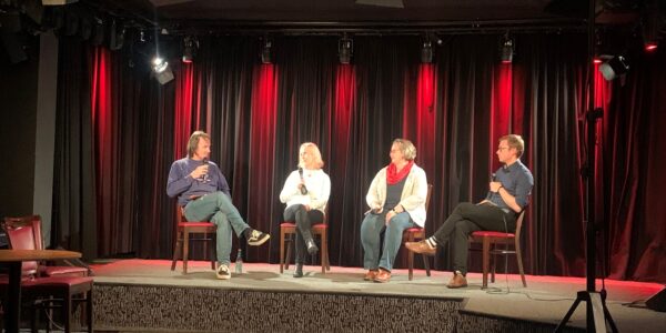 vier Menschen tauschen sich auf einer Bühne aus