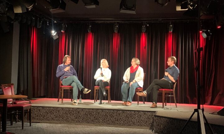 vier Menschen tauschen sich auf einer Bühne aus