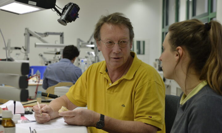 Zahntechnikmeister prüft modellierte Ersatzzähnen mit Auszubildenen.