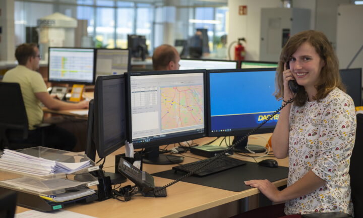 Junge Frau im Büro telefoniert und lacht in die Kamera.