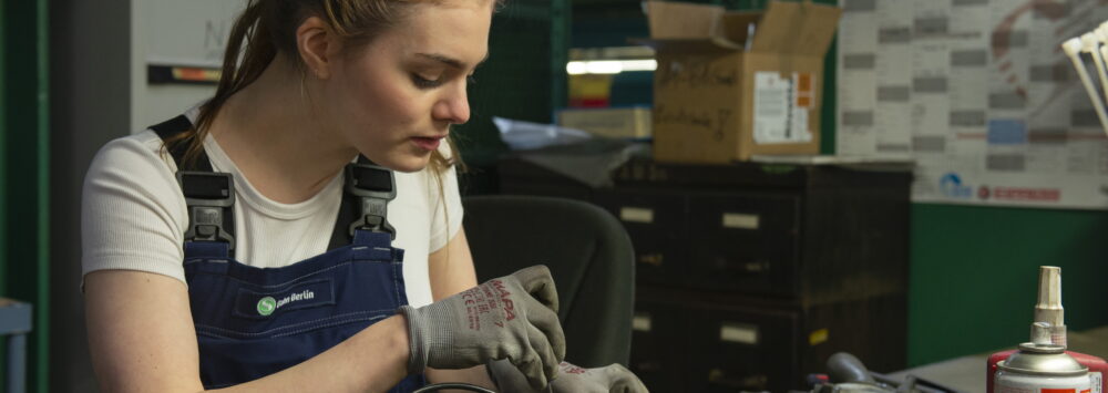 Junge Frau trägt Blaumann mit der Aufschrift 