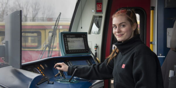 Junge Frau mit schwarzer Fleecejacke der Deutschen Bahn sitzt in der S-Bahn und bedient den Schalthebel