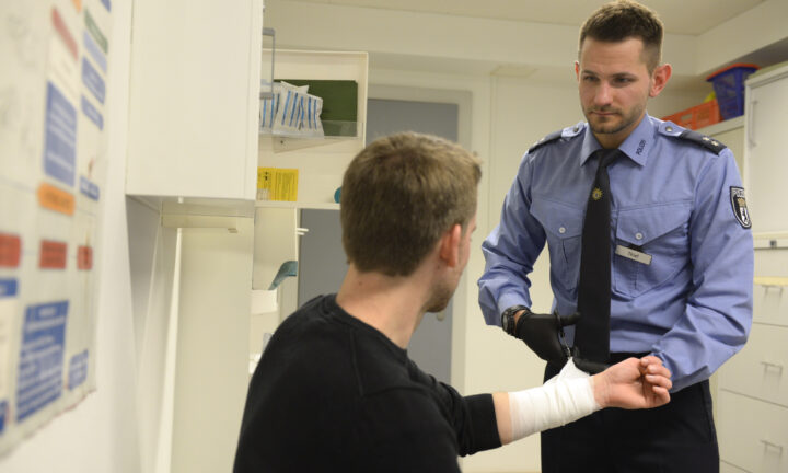 Polizist verarztet jungen Mann und löst diesem sein Verband.