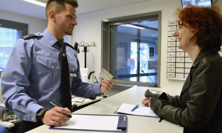 Polizist nimmt auf der Wache Daten einer Frau auf.