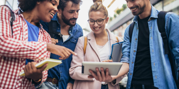 Eine Gruppe junger Menschen schaut sich den Bildschirm eines IPads an.
