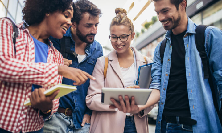 Eine Gruppe junger Menschen schaut sich den Bildschirm eines IPads an.