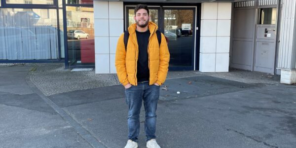 Ein junger Mann mit gelber Jacke steht auf der Straße