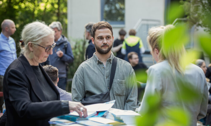 drei Personen sind im Gespräch, in der Mitte ein junger Mann