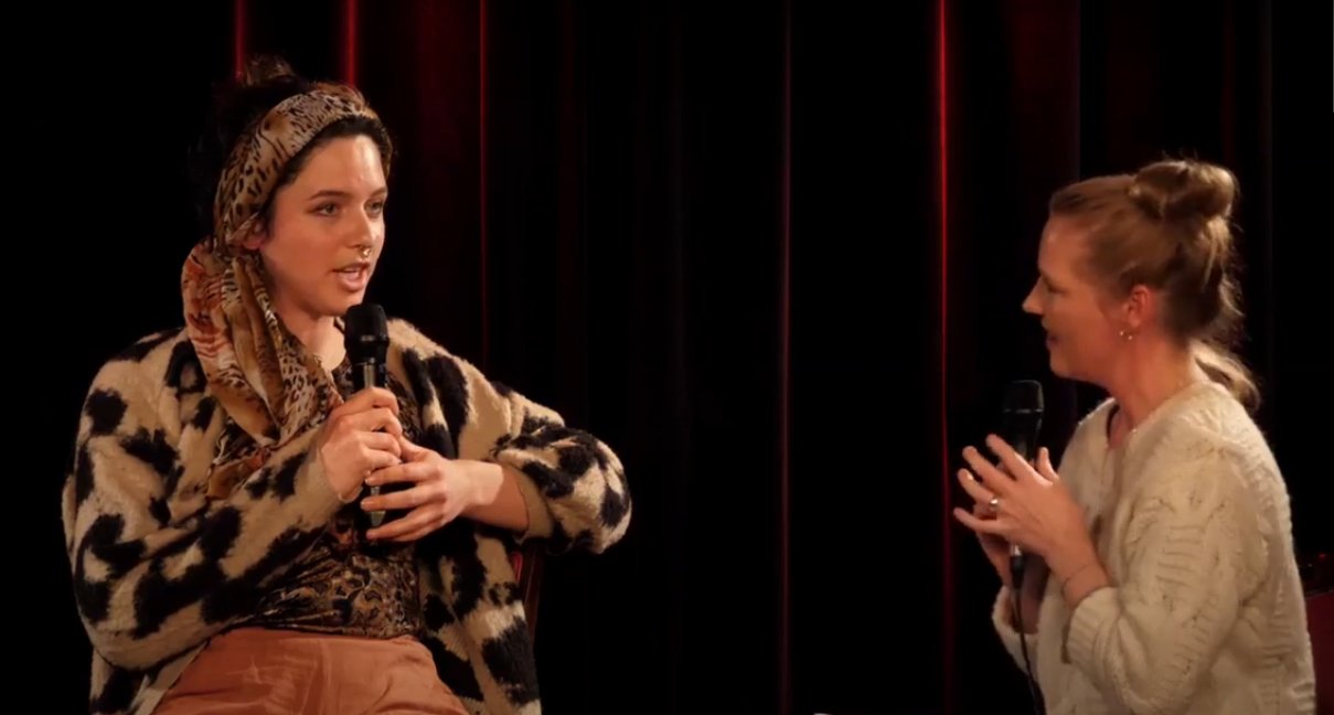 Eine junge Studienabbrecherin berichtet auf der Bühne von ihrem Werdegang bei der Fuckup:Studienabbruch im November 2021 in Hannover. Die Moderatorin hört ihr zu.