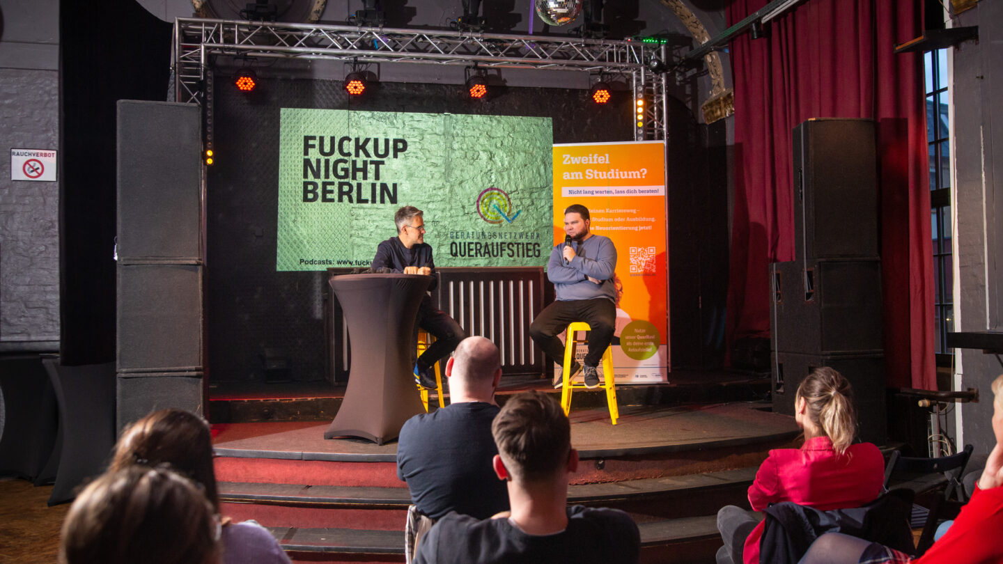 Ein junger Mann sitzt mit dem Moderator auf der Bühne.