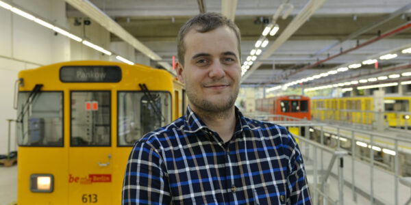 Ein junger Mann, im Hintergrund eine S-Bahn.