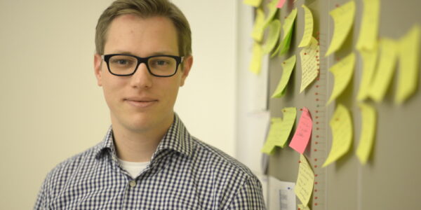 Ein junger Mann mit Brille schaut in die Kamera