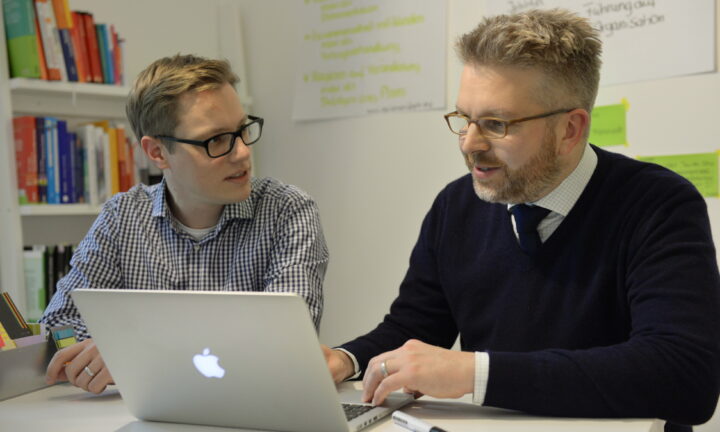 Ein junger und ein mittelalter Mann am Laptop