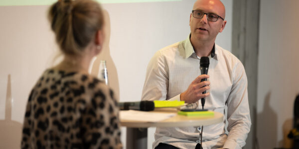 Ein junger Mann sitzt auf der Bühne und spricht in das Mikrofon