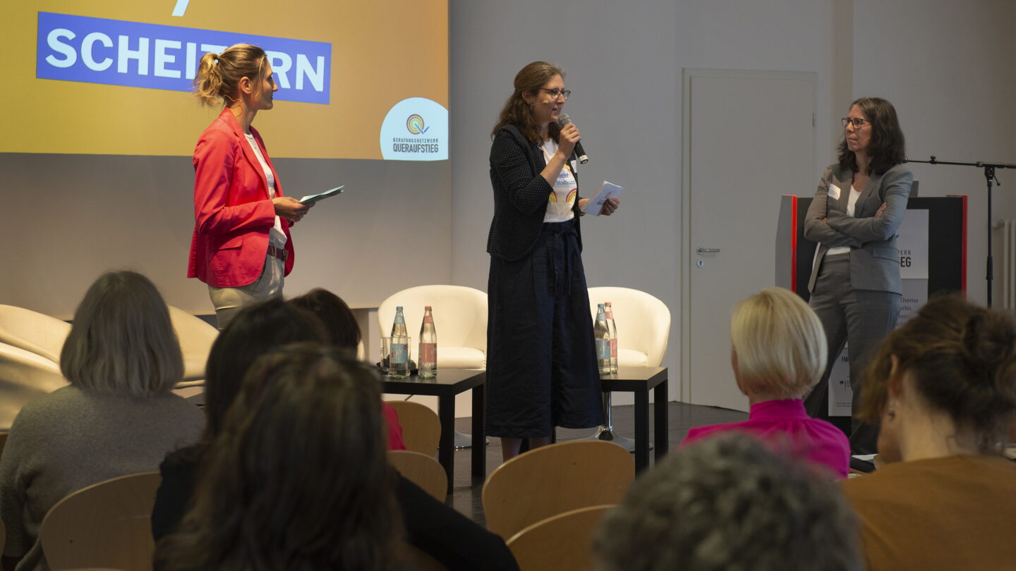 Drei Frauen stehen auf der Bühne und halten eine Ansprache vor dem Publikum