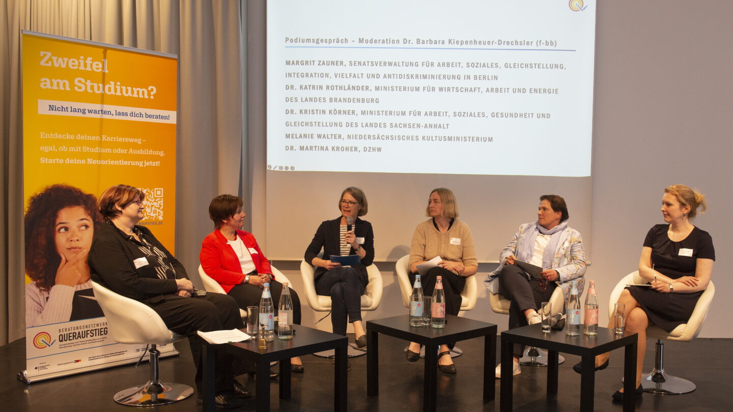 Sechs Frauen sitzen auf Stühlen auf einer Bühne und moderieren eine Gesprächsrunde