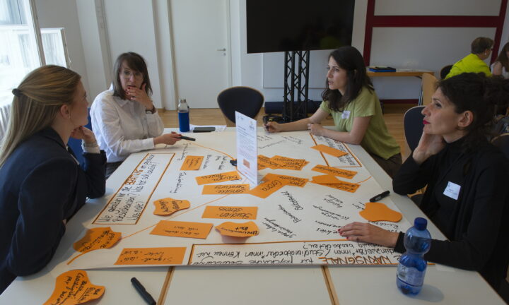 Eine Gruppe von Frauen sitzt um einen Tisch herum und beschriftet ein Poster