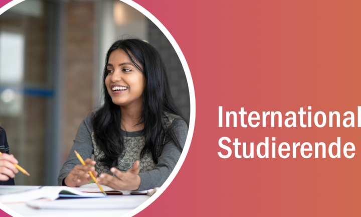 Zwei junge Studentinnen sitzen an einem Tisch mit Unterlagen, halten Bleistifte in der Hand und unterhalten sich miteinander.