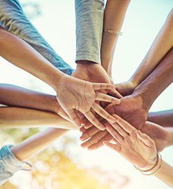 Eine Gruppe verschiedener Menschen legt die Hände übereinander.