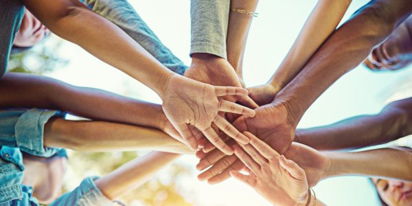 Eine Gruppe verschiedener Menschen legt die Hände übereinander.