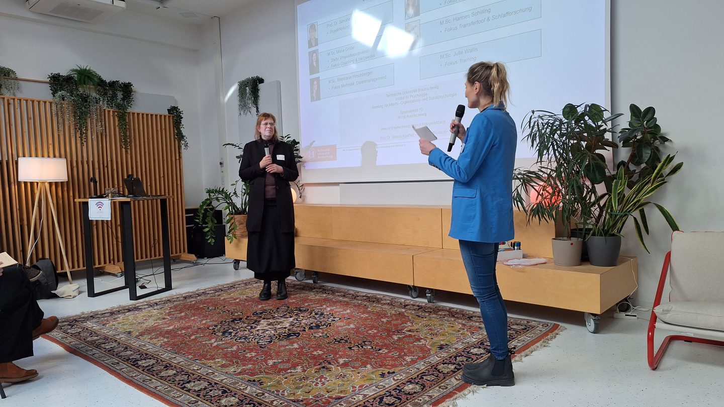 Zwei Frauen stehen auf der Bühne und sprechen miteinander.