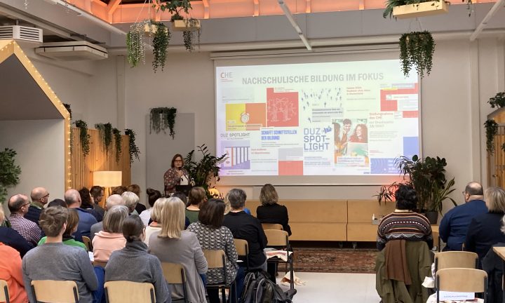 Eine Frau steht am Rednerpult vor einer Präsentation und spricht zum Publikum.