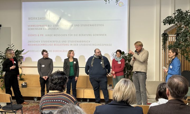 Fünf Männer und Frauen stehen zusammen mit zwei Moderatorinnen auf der Bühne und sprechen nacheinander zum Publikum.